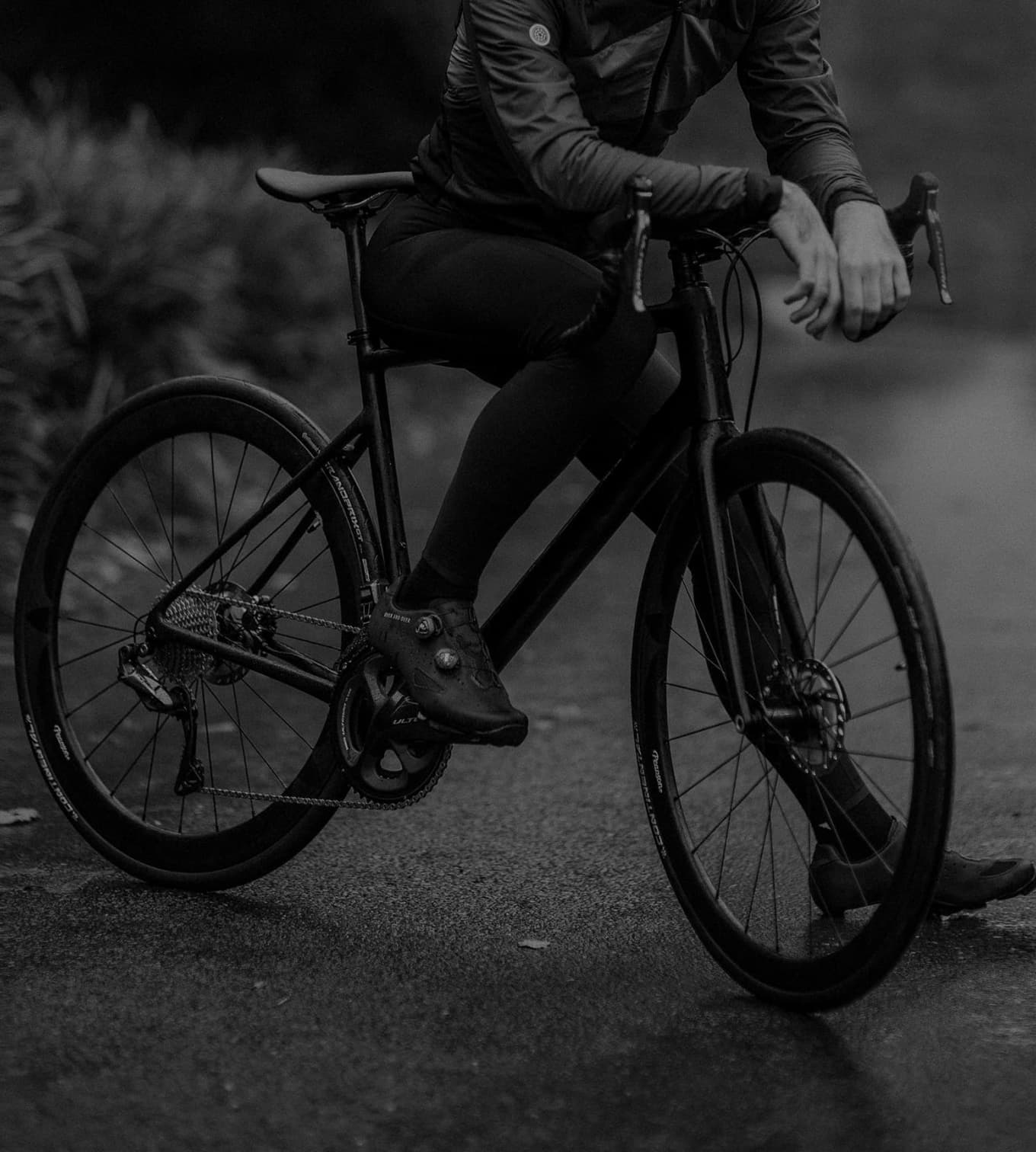 Pessoa em cima de uma bicicleta, parada apoiando um dos pés no chão e com os braços apoiados no guidão.